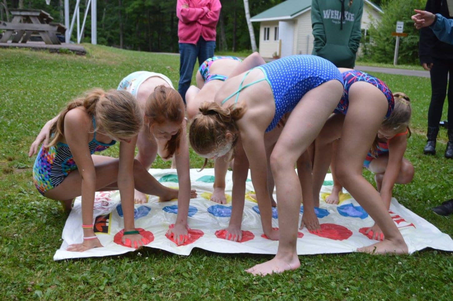 Campers at WeHaKee Camp for Girls playing twister outside using colored shaving cream.
