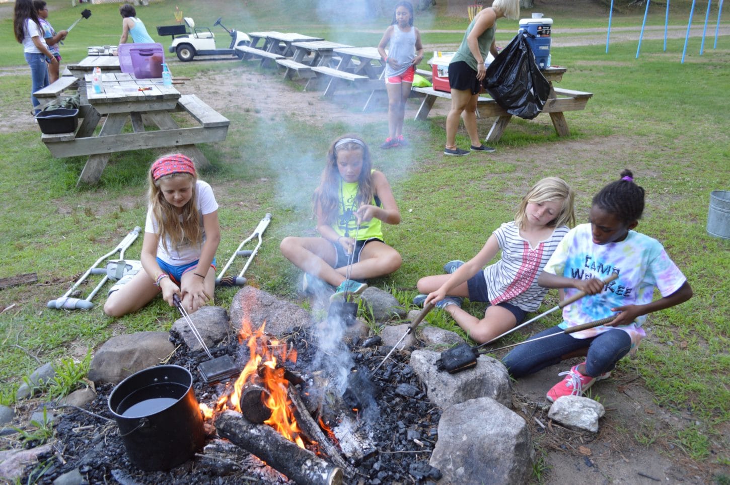 Campers making pudgy pies at the fire for supper at WeHaKee Camp for Girls.