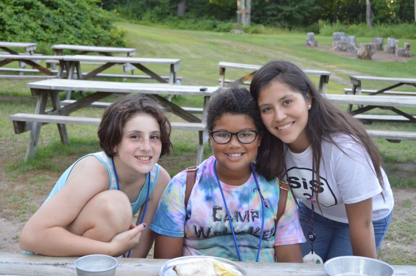Camper friends hanging out around the picnic tables at WeHaKee Camp for Girls.