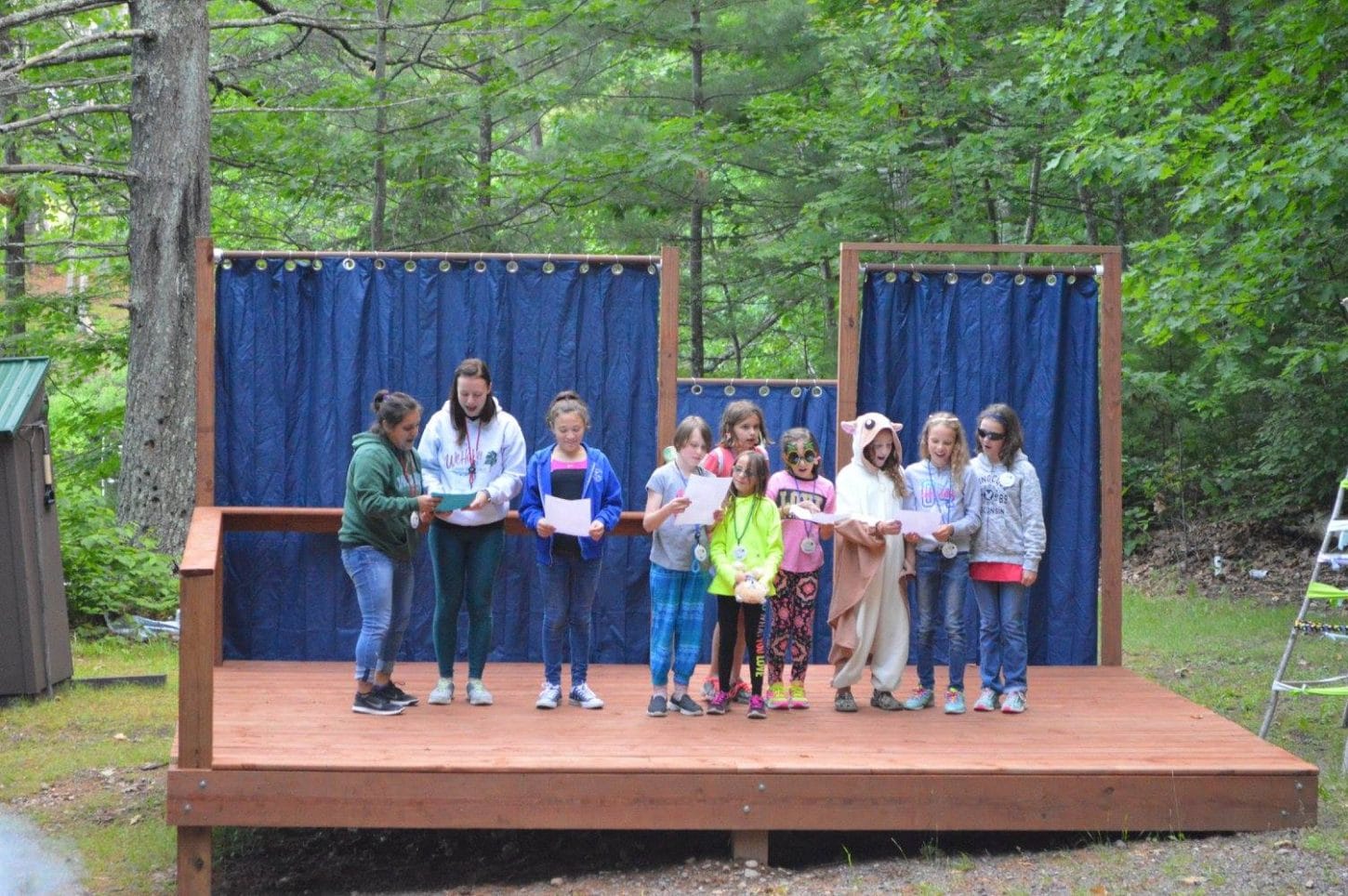 WeHaKee Camp for Girls campers and staff reading a skit on the outdoor stage.