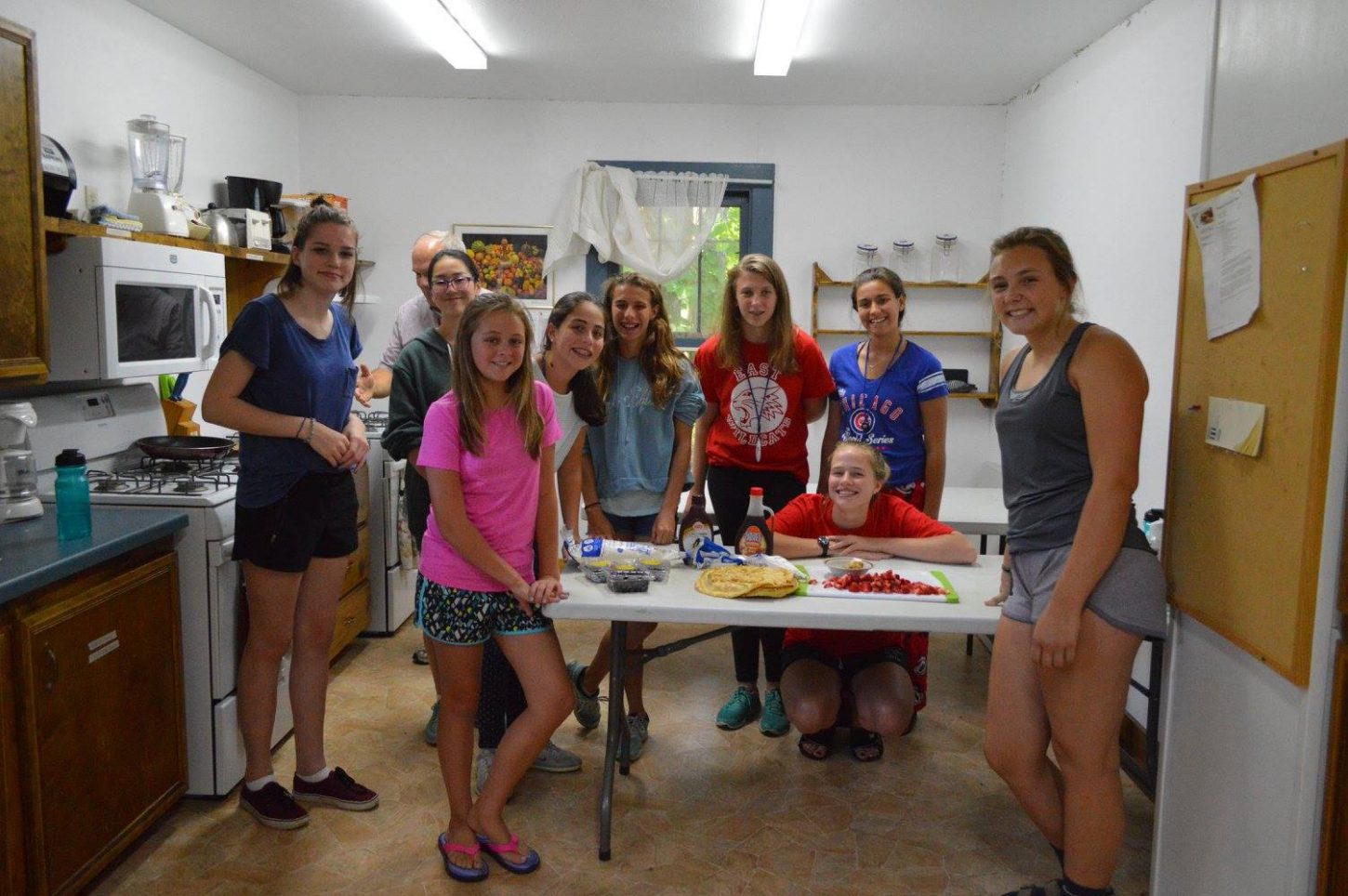 WeHaKee girls posing around a table as they make a strawberry dessert