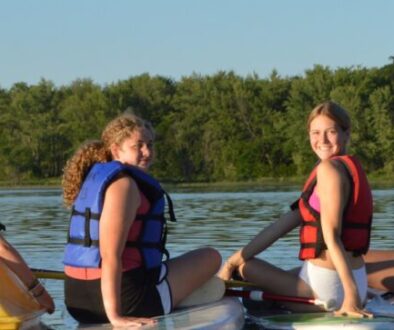 WeHaKee Camp for Girls campers posing on their kayaks and paddleboards, smiling during a fun summer day on Hunter Lake.